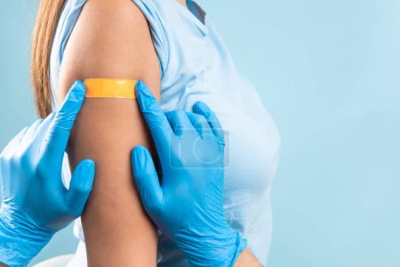 Foto de Doctor hands putting a plaster at female arm after injection of a corona virus vaccine. Coronavirus protection, vaccination concept - Imagen libre de derechos