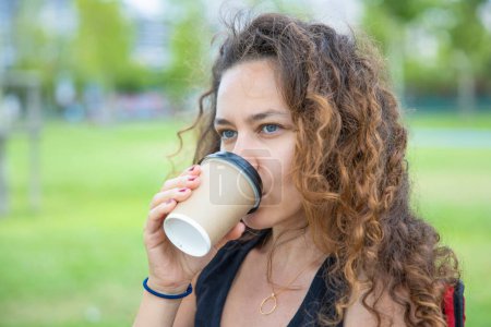 Photo for Young woman drinking coffee in the public par - Royalty Free Image
