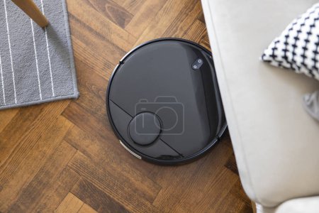 Téléchargez les photos : Robot vacuum cleaner on the parquet floor. Cleaning in living room at home - en image libre de droit