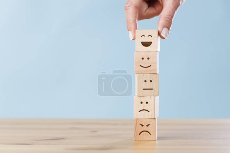 Photo for Woman hand chooses smiley face on wooden block cube - Royalty Free Image
