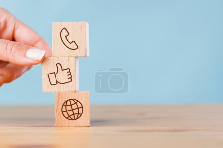 Photo for Female hand putting wooden block cube symbol telephone, thumbs up, world globe. Website page contact us or social media concept - Royalty Free Image