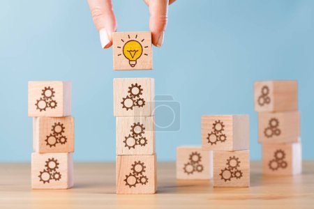 Photo for Woman hand building wood block cubes stacking on top. Light bulb and gears. Solution concepts idea and innovation - Royalty Free Image