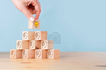 Photo for Woman hand picked wooden cube block with head human symbol and light bulb icon. Creative idea and innovation. - Royalty Free Image