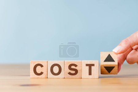 Photo for Hand showing the up and down movement of the word 'cost' written on wooden cube blocks - Royalty Free Image