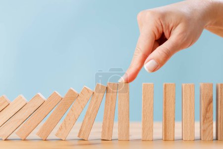 Photo for Business woman's finger try to stopping falling wooden dominoes blocks for business solution concept. Business crisis effect or risk protection concept - Royalty Free Image