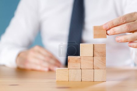 Businessman arranging wood block stacking. Business concept for growth success process