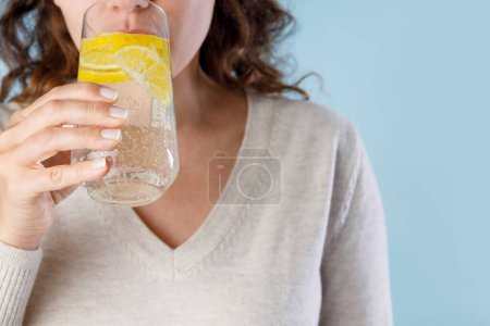 Téléchargez les photos : Jeune femme boire de l'eau minérale avec lim - en image libre de droit