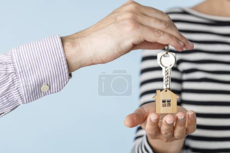 Téléchargez les photos : Gros plan de la main du vendeur masculin de maison appartement bureau tenant clés le donnant à la jeune femme acheteur après la conclusion de l'affaire et obtenir l'acompte - en image libre de droit