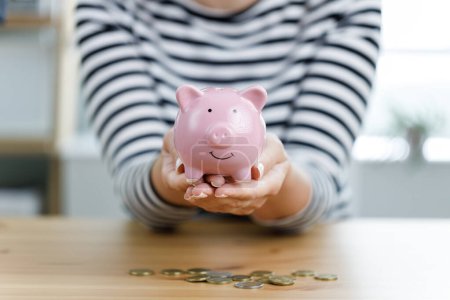 Photo for Woman hands holding piggy bank on wooden table. Saving money and financial investmen - Royalty Free Image