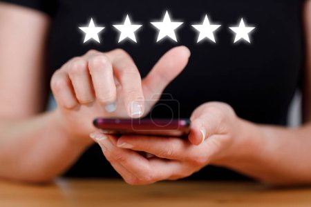 Photo for Woman using smartphone with five stars for customer review product and service concept - Royalty Free Image