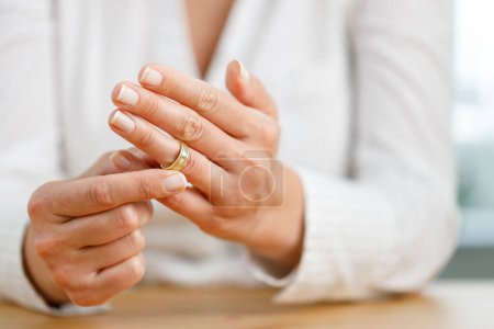 Foto de Manos de mujer que está a punto de quitarse su anillo de bodas. Concepto de divorcio - Imagen libre de derechos