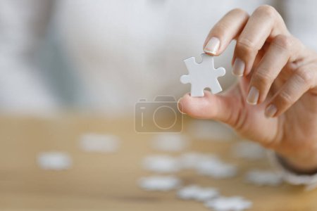Photo for Woman's hand showing a jigsaw puzzle piece on wooden table. Healthcare for alzheimer disease, memory loss and mental health concept - Royalty Free Image