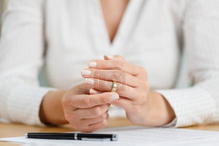 Hands of female who is about to taking off her wedding ring. Divorce concept