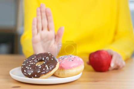 Téléchargez les photos : Jeune femme refuse la malbouffe tout en choisissant de manger des fruits frais sains pour sa santé. Bonne nourriture pour un concept sain - en image libre de droit