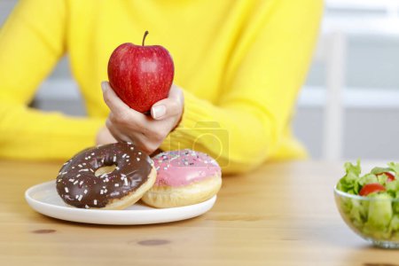Foto de Elegir entre donut y manzana. Buena nutrición para un cuerpo sano - Imagen libre de derechos
