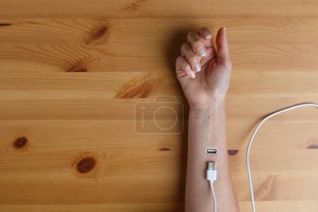 Photo for Woman who will charge herself from the implant in her wrist with a usb cable - Royalty Free Image