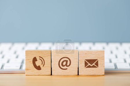 Kommunikationsikonen auf Holzwürfelblöcken und vor einer Tastatur. Kontaktieren Sie uns oder E-Mail-Marketing-Konzept 