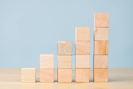 Foto de Bloques de madera que aumentan la barra del gráfico, diagrama infográfico, gráfico hecho de bloques de madera por delante en el fondo azul - Imagen libre de derechos