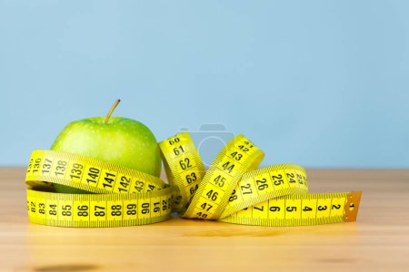 Téléchargez les photos : Un ruban à mesurer enveloppé autour d'une pomme verte. Alimentation saine et concept de régime alimentaire. - en image libre de droit