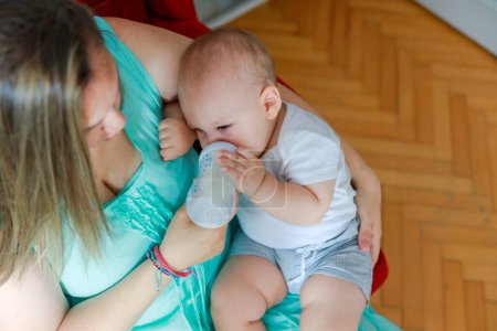 Téléchargez les photos : Mère heureuse nourrit son bébé garçon à la maison - en image libre de droit