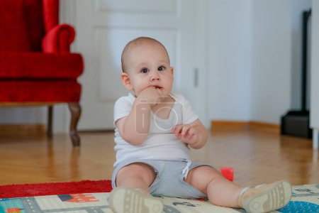 Foto de Niño sentado en el salón. Él está mirando a su alrededor mientras juega con juguetes - Imagen libre de derechos