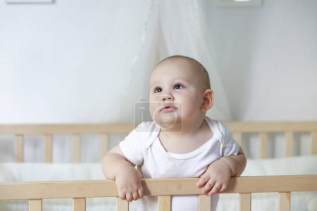 Photo for Little cute baby stand in the baby cot - Royalty Free Image