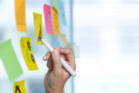 Photo for Business woman writing on colorful sticky note paper. Highlights the growth char - Royalty Free Image