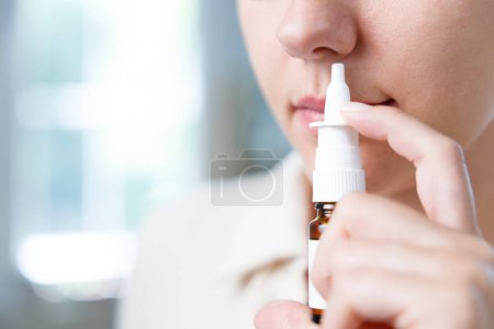 Téléchargez les photos : Gros plan sur une jeune femme malade utilisant un spray nasal - en image libre de droit