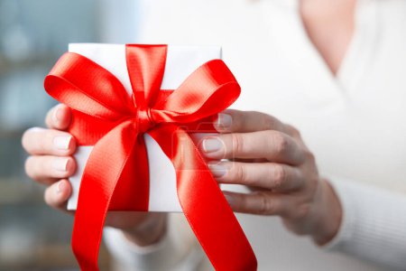 Photo for Woman showing white small gift box with red ribbo - Royalty Free Image