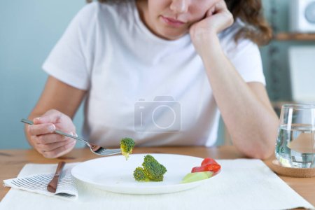 Photo for First day of diet. Unhappy young woman looking at small broccoli portion on the plate - Royalty Free Image