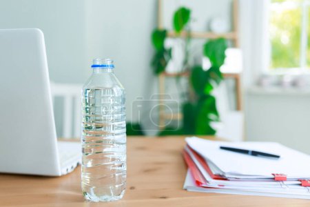 Eine Flasche Wasser steht auf dem Schreibtisch. Die Bedeutung des Trinkwassers am Tag