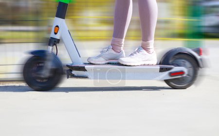 Téléchargez les photos : Jeune femme équitation électrique coup de pied scooter dans le par - en image libre de droit