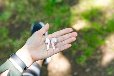 Photo for Woman hand holding a portable white wireless headphones - Royalty Free Image