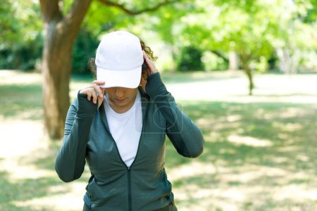 Photo for Athletic young woman wearing a white baseball cap in the woods - Royalty Free Image
