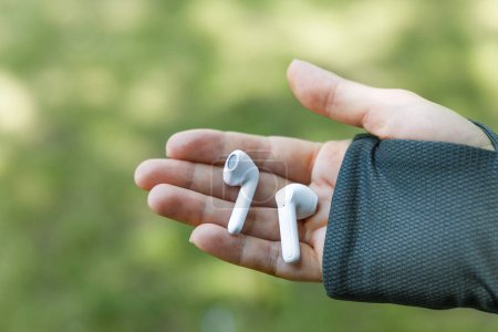 Photo for Woman's hands holding a portable gadget white wireless headphones - Royalty Free Image