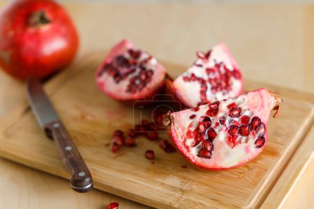 Photo for Juicy fresh pomegranates lie on a table on a wooden cutting boar - Royalty Free Image
