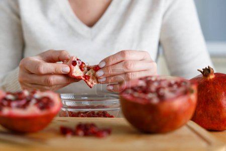 Photo for Young woman peel a pomegranate. Close up sho - Royalty Free Image