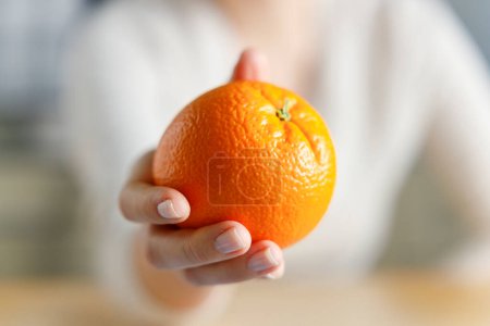 Foto de Primer plano sobre la fruta naranja en la mano de las mujeres jóvenes - Imagen libre de derechos