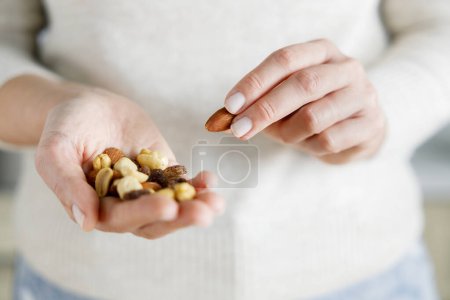 Foto de Primer plano de nueces en manos de mujer. Mujer sosteniendo bocadillo saludable - Imagen libre de derechos