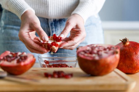 Photo for Young woman peel a pomegranate. Close up sho - Royalty Free Image