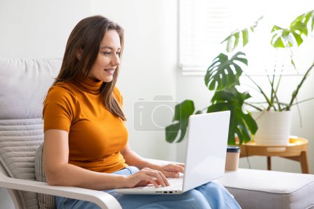 Foto de Mujer joven usando el ordenador portátil en casa. Trabajo a domicilio o compras en línea, educación a distancia, educación en línea, comercio electrónico, freelance concep - Imagen libre de derechos