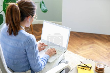 Foto de Freelancer mujer joven que trabaja en el ordenador portátil. Concepto de trabajador independiente. Pantalla blanca en blanco con spac de copia - Imagen libre de derechos
