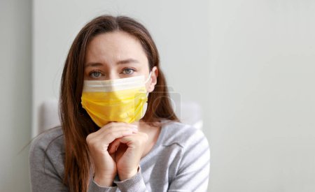 Téléchargez les photos : Jeune femme en masque médical restant à la maison en quarantaine - en image libre de droit