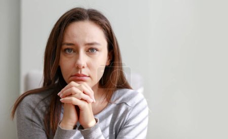 Foto de Mujer joven estresada mirando a la ventana sentada en el sofá en hom - Imagen libre de derechos