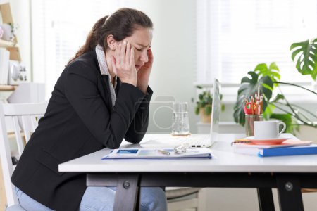 Foto de Mujer de negocios estresada que sufre de dolor de cabeza trabajando en casa oficina - Imagen libre de derechos
