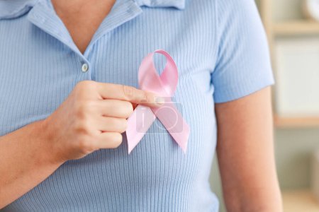 Woman putting on a pink breast cancer awareness ribbon