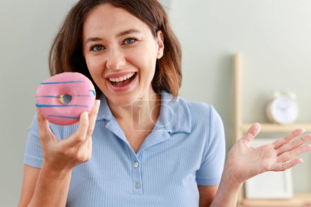 Foto de Hermosa mujer joven con chips de chocolate rosa donut - Imagen libre de derechos