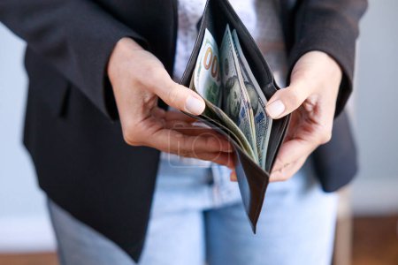 Téléchargez les photos : Gros plan des mains de femme d'affaires avec portefeuille et billets de cent dollars - en image libre de droit