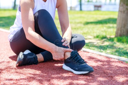 Photo for Young woman sitting in track field and suffering from an ankle injury during her workout - Royalty Free Image