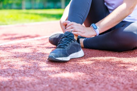 Photo for Young woman sitting in track field and suffering from an ankle injury during her workout - Royalty Free Image